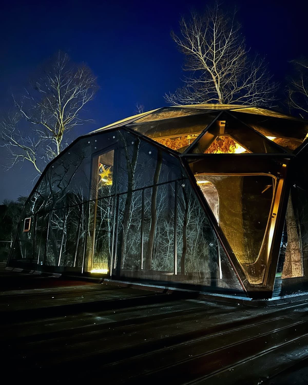 Mirrored dome spa glowing at night in a forest