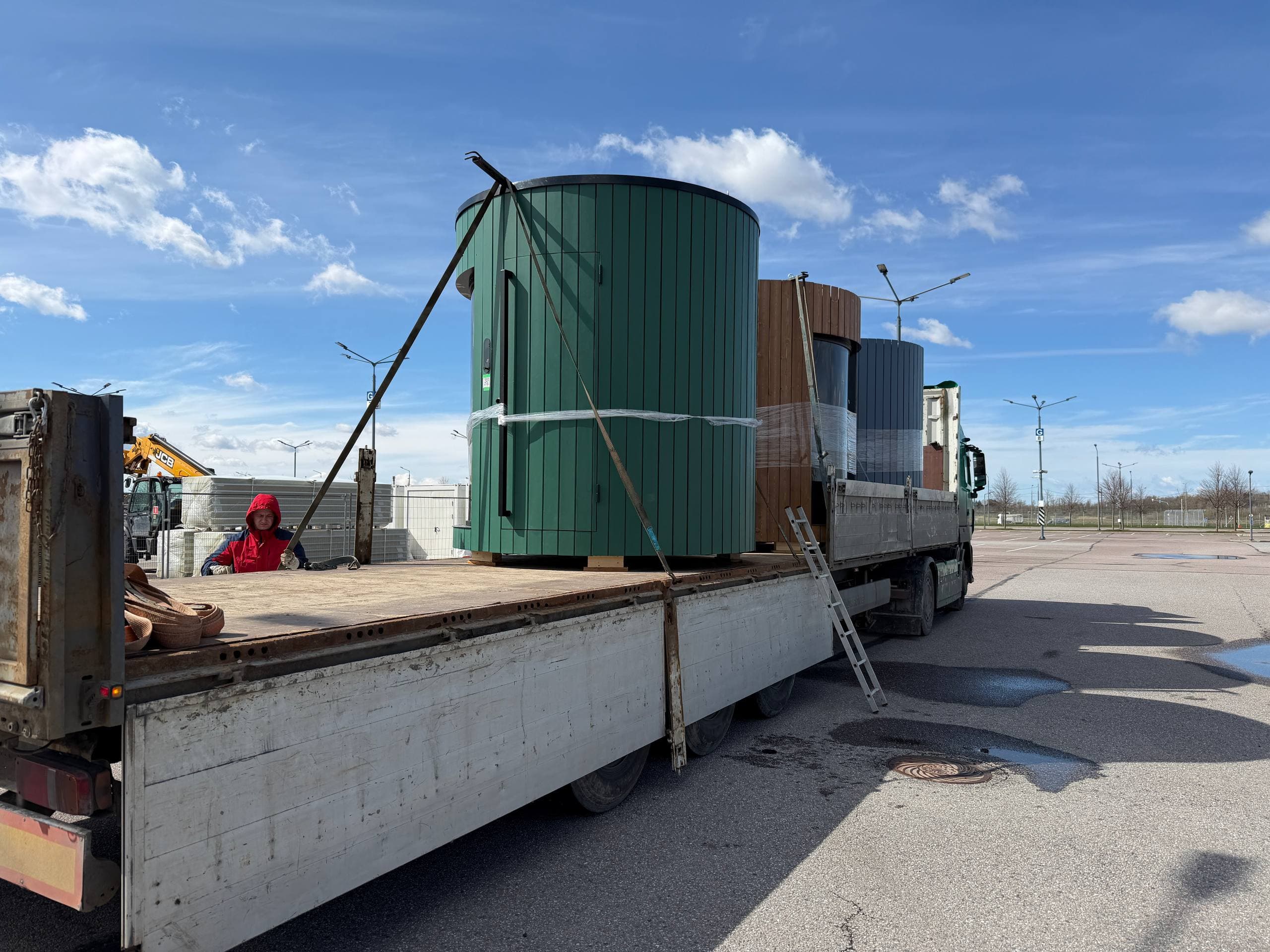 Green cylindrical sauna secured on a flatbed trailer